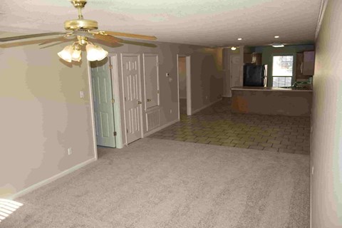 A room with a ceiling fan and a door leading to another room.