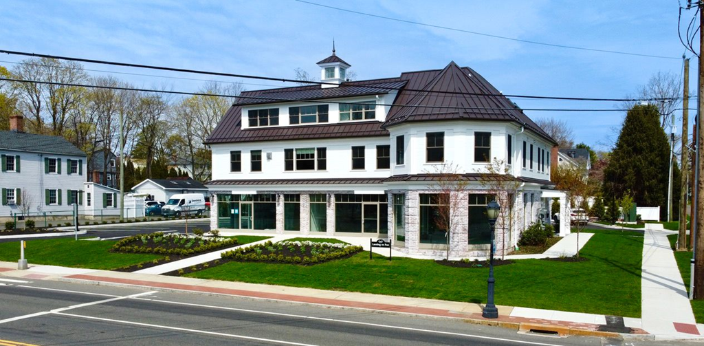 A white house with a brown roof and a black lamp post in front.