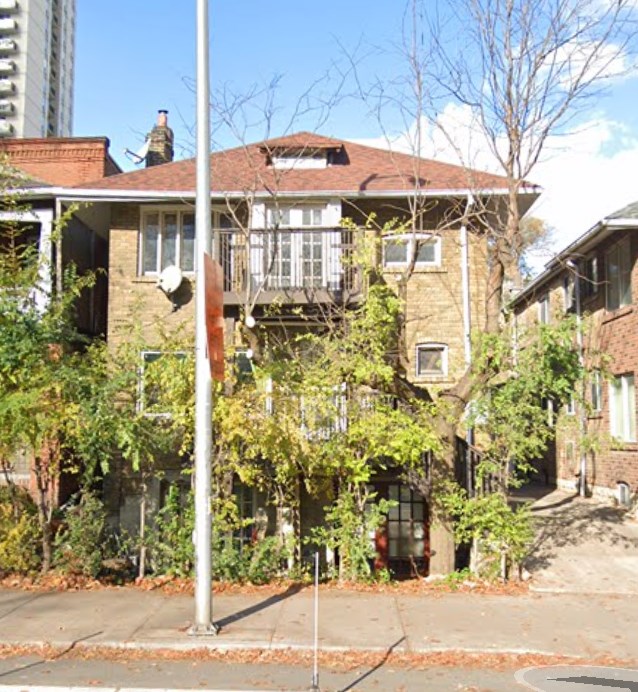 A tree in front of a brick building.