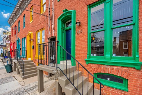 A red brick building with green trim and a blue door.