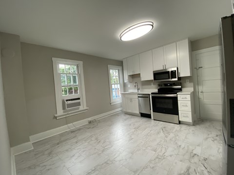 A kitchen with white cabinets and a marble floor.