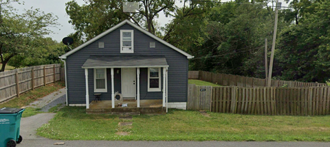 A small blue house with a white door and a porch.