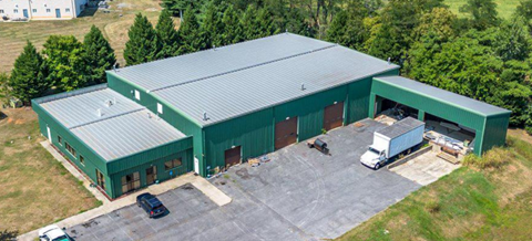 A large green building with a truck parked in front.