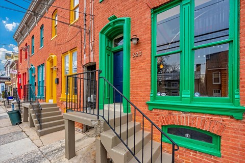 A red brick building with green trim and a blue door.