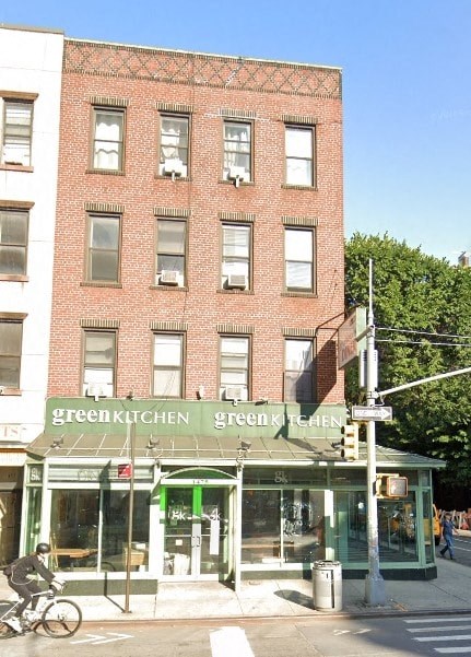 A red brick building with a green awning that says Green Kitchen.