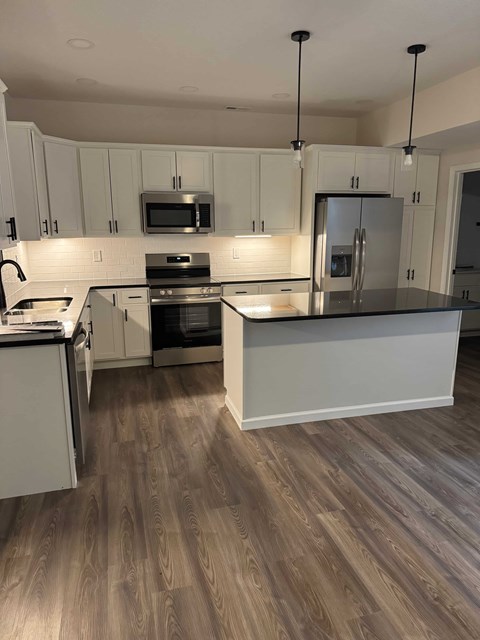 A kitchen with white cabinets and a wooden floor.