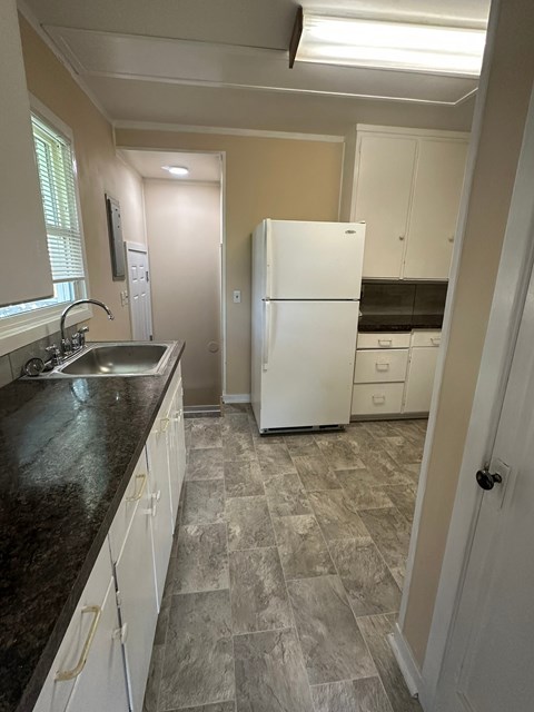 A kitchen with a white fridge and a black counter top.