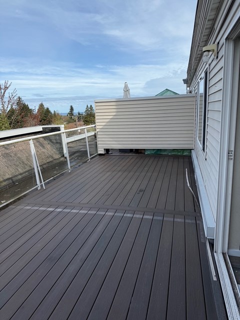 A wooden deck with a white railing and a white house.