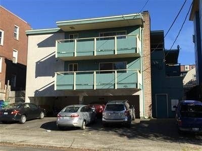 A parking lot with cars and a building with balconies.