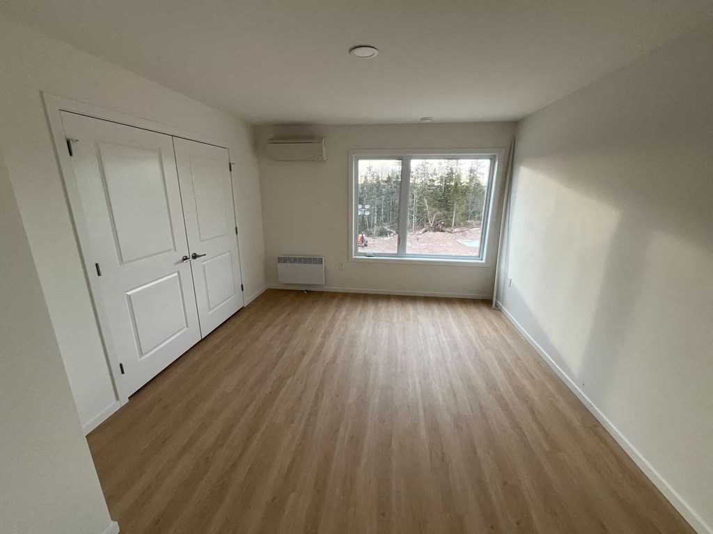 A room with wooden flooring and white walls.