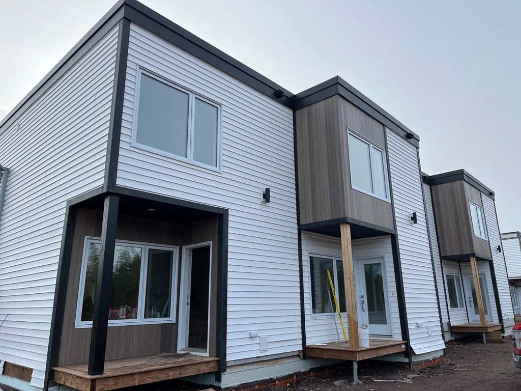 A row of houses with white siding and dark trim.