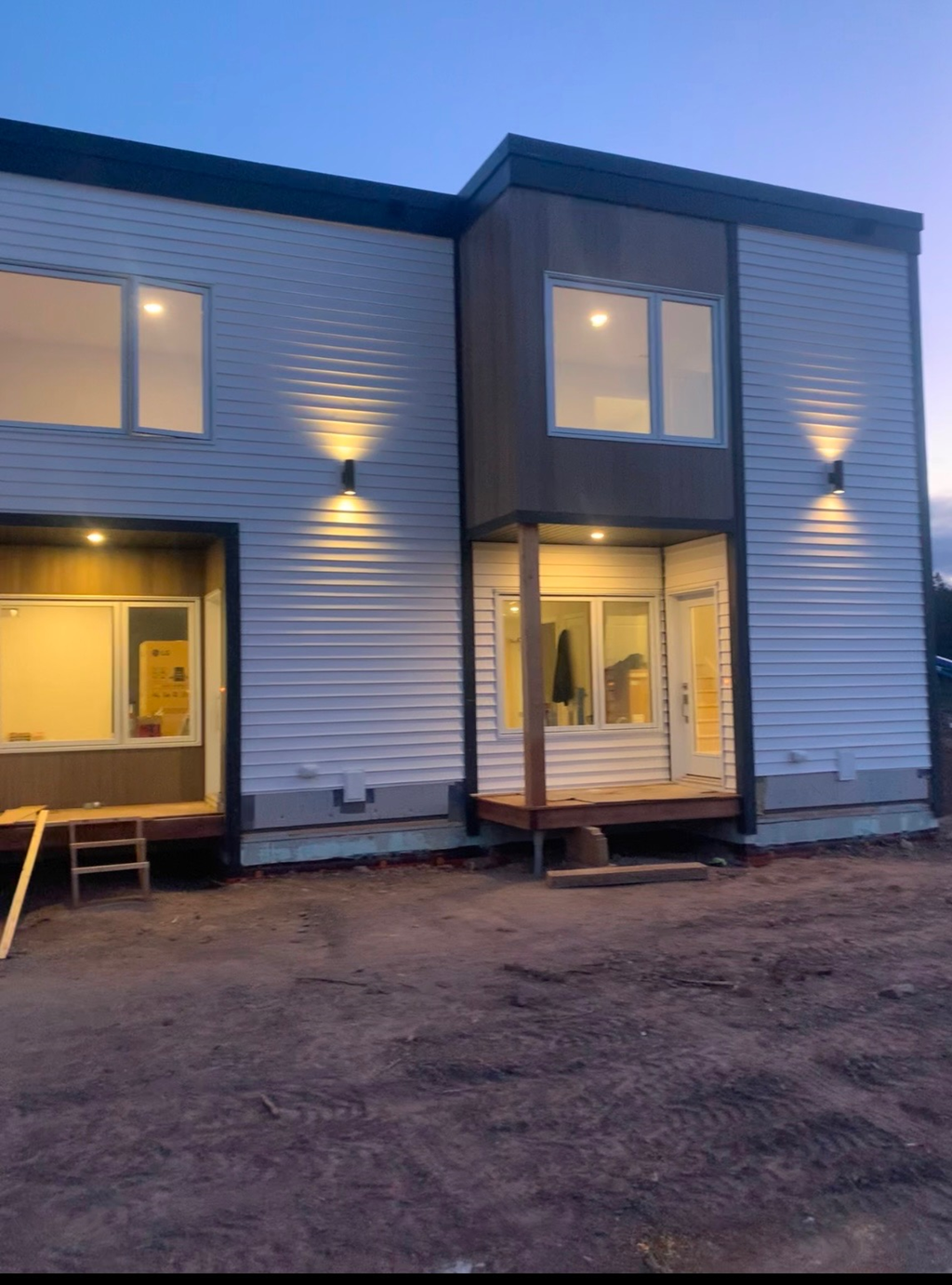 A modern house with a grey exterior and a white door is shown.
