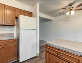 A white refrigerator is in a kitchen with wooden cabinets.