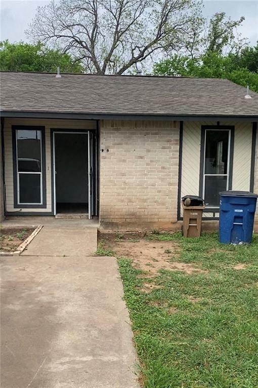 A small house with a blue trash can in front.