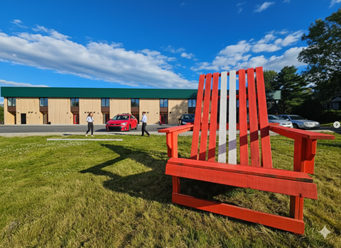 A red and white striped bench sits in the foreground of a grassy area.