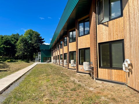 A long building with a green roof and wooden exterior.