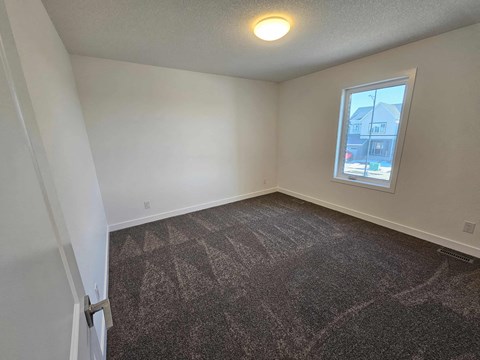 A room with a carpeted floor and a window showing a building outside.