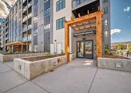 A modern building with a wooden entrance gate and planters in front.