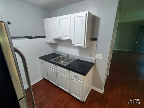 A kitchen with white cabinets and a black countertop.