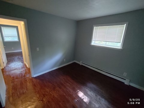 A room with a wooden floor and a window with blinds.