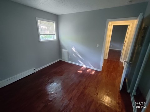 A room with wooden floors and a window letting in sunlight.