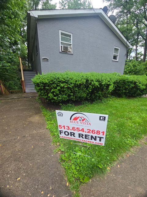 A blue house with a sign in front that says "For Rent".