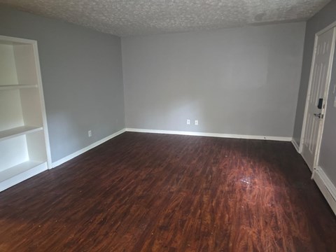A room with wooden flooring and white walls.