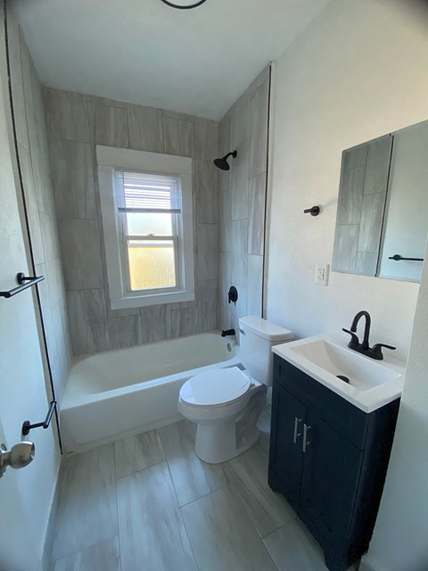 A bathroom with a white tub, toilet, and sink.