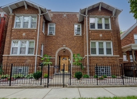 A red brick house with a black iron fence in front.