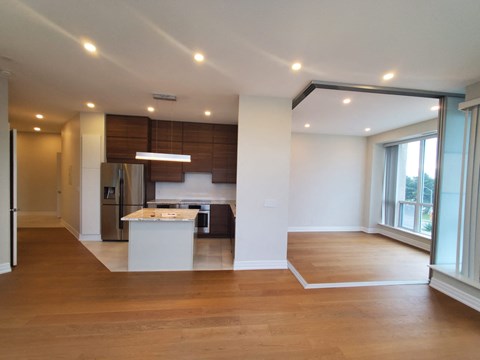 A spacious kitchen with a refrigerator, sink, and stove is located in the center of the room.