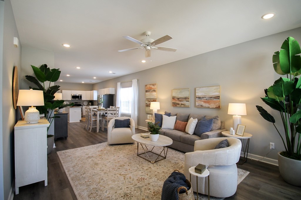 A living room with a white couch, a white side table, and a white ceiling fan.