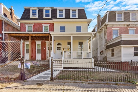 A house with a red door is in front of a house with a white door.