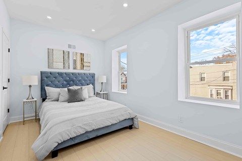 A bedroom with a large bed and a window showing a building outside.