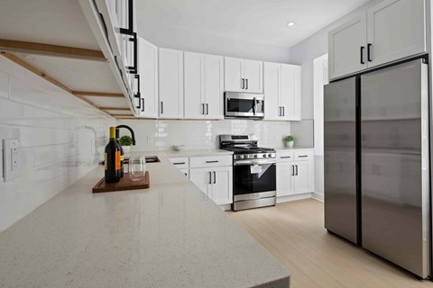 A kitchen with white cabinets and a stainless steel refrigerator.
