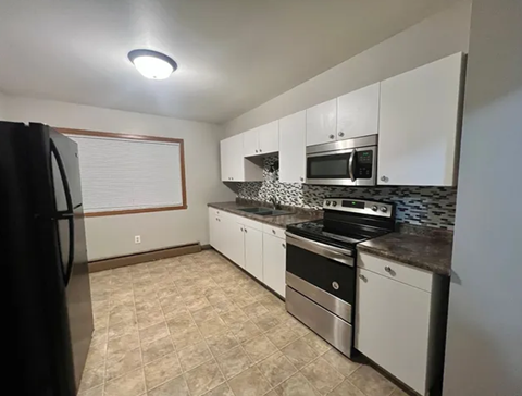 A kitchen with white cabinets and black appliances.