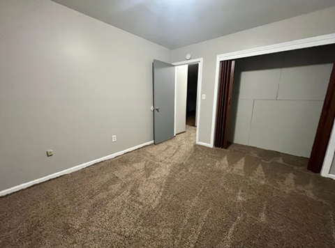 A room with a carpeted floor and a door on the left side.
