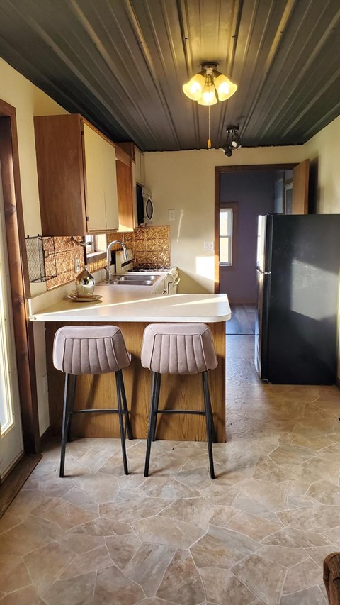 A kitchen with a bar stool and a fridge.