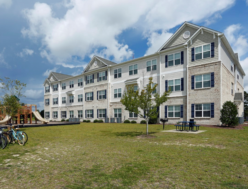 a large apartment building with a yard and a playground