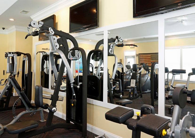 a gym with various machines and televisions on the wall
