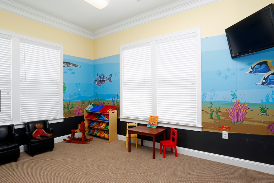 a childs play room with a mural on the wall and a table and chairs