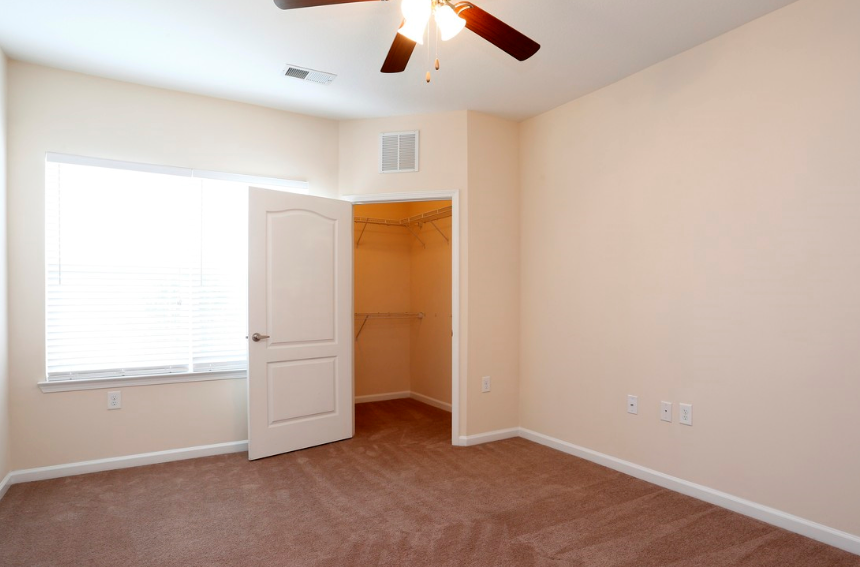 a bedroom with a closet and a window and a ceiling fan