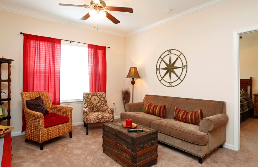 a living room with a couch and chairs and a ceiling fan