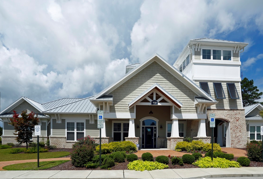 the front of a building with a blue sky and white clouds