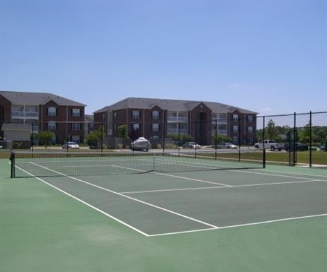a tennis court in front of an apartment building