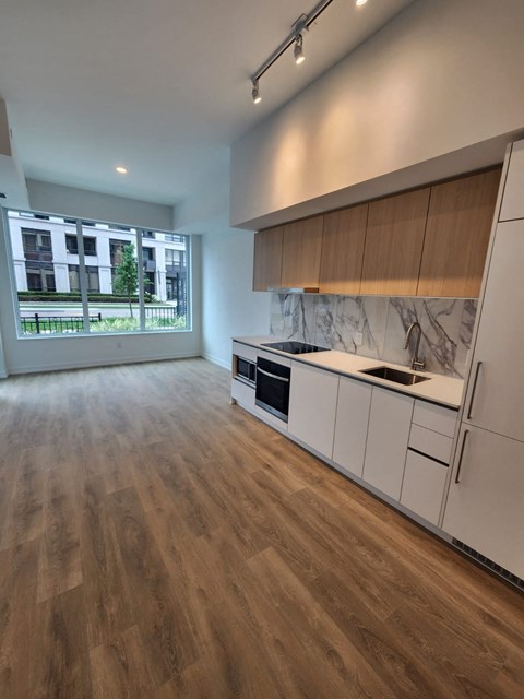 A kitchen with white cabinets and a marble countertop.