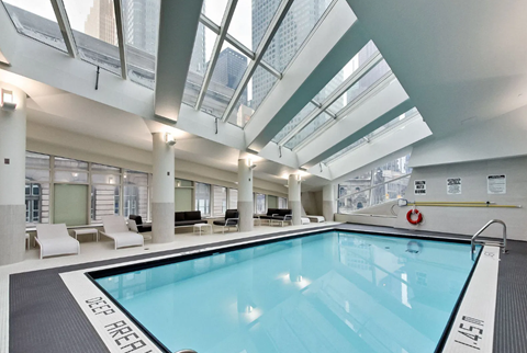 A swimming pool inside a building with a glass ceiling.