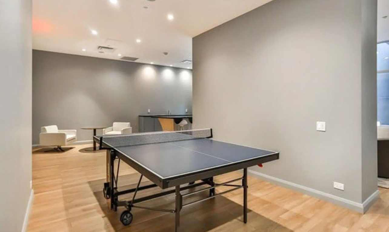 A ping pong table is in the middle of a room with a wooden floor.