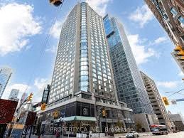 A tall building with a glass facade stands in the middle of a city street.