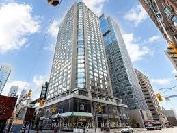 A tall building with a glass facade stands in the middle of a city street.