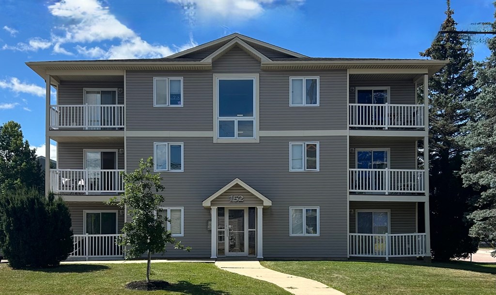 A grey apartment building with a white tree in front.